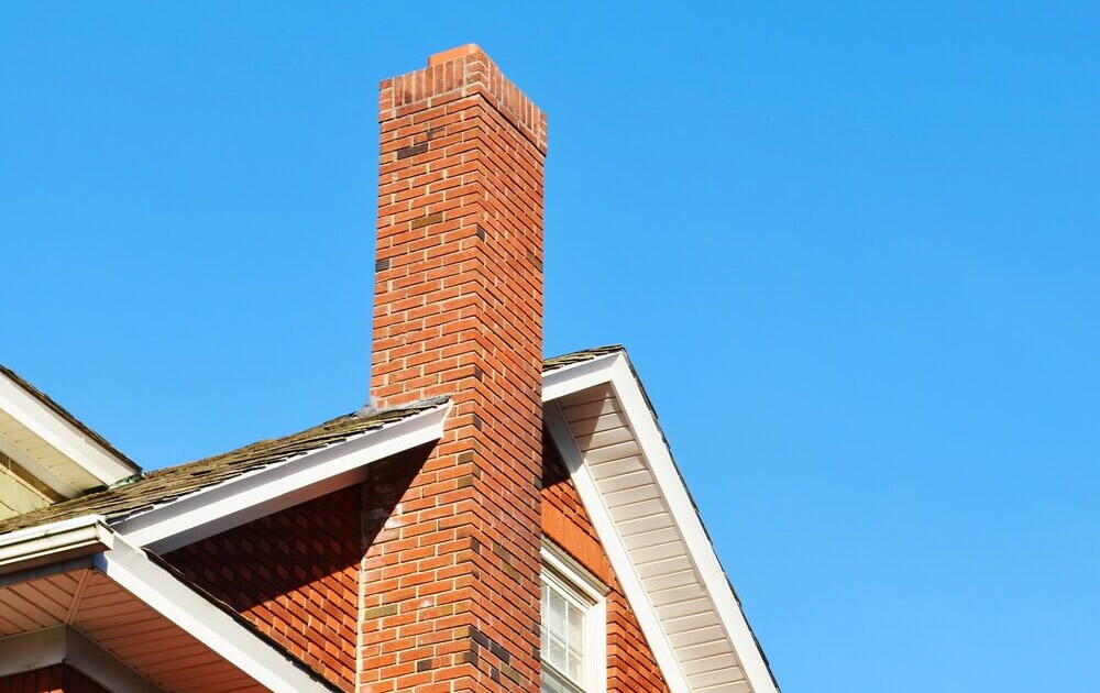 Brick Chimney beside a house and the sky in the background. Chimney Service Repair in Dallas Texas by ALC Chimney Service.