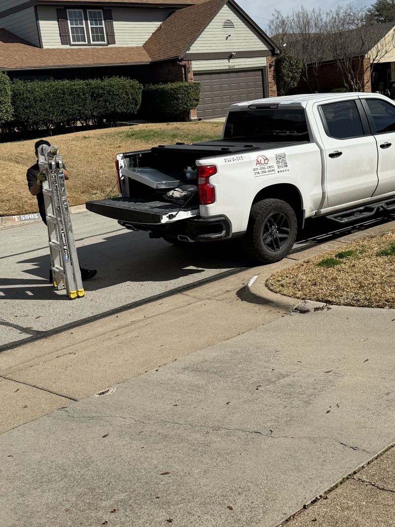 An ALC technician unloading equipment from the company work truck on a residential driveway
