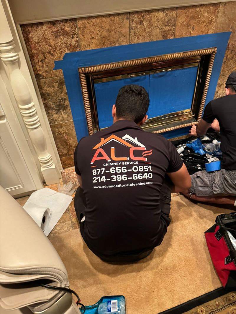 An ALC Chimney technician in branded uniform working at a fireplace opening