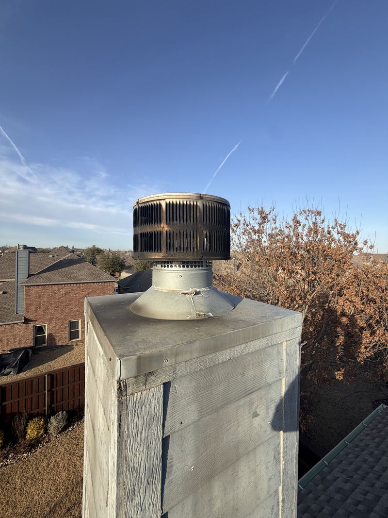 A finished chimney chase with a new metal chase cover and round flue cap