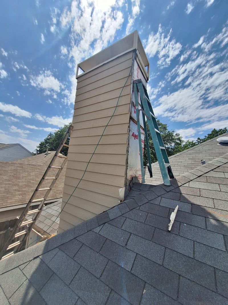 A chimney chase reclad with new siding, seen from the roofline
