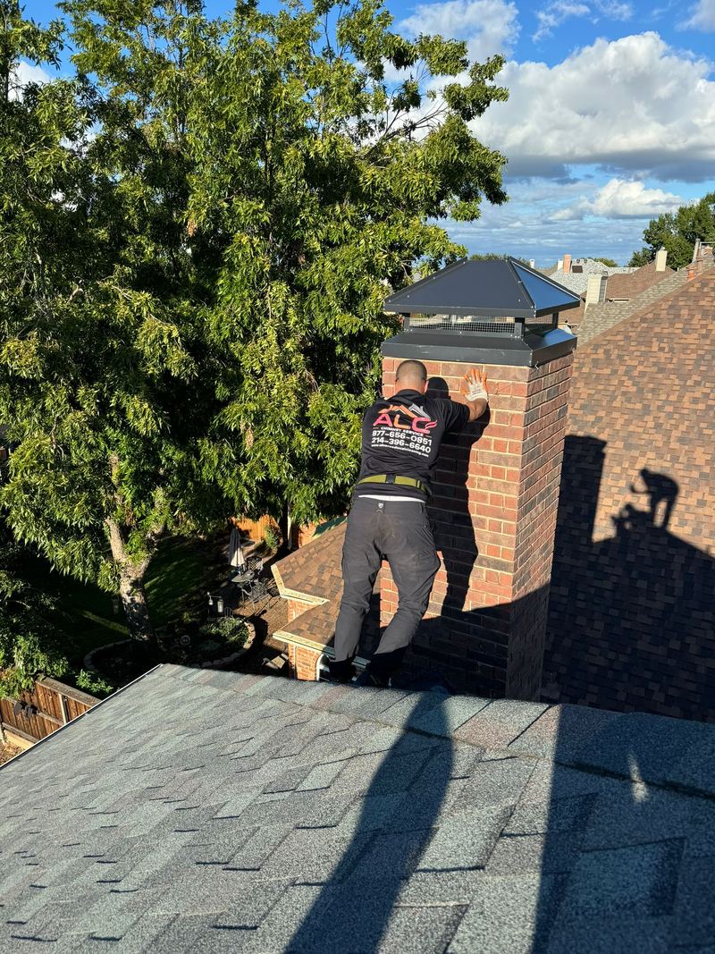 Two ALC technicians working together on a chimney on a shingle roof