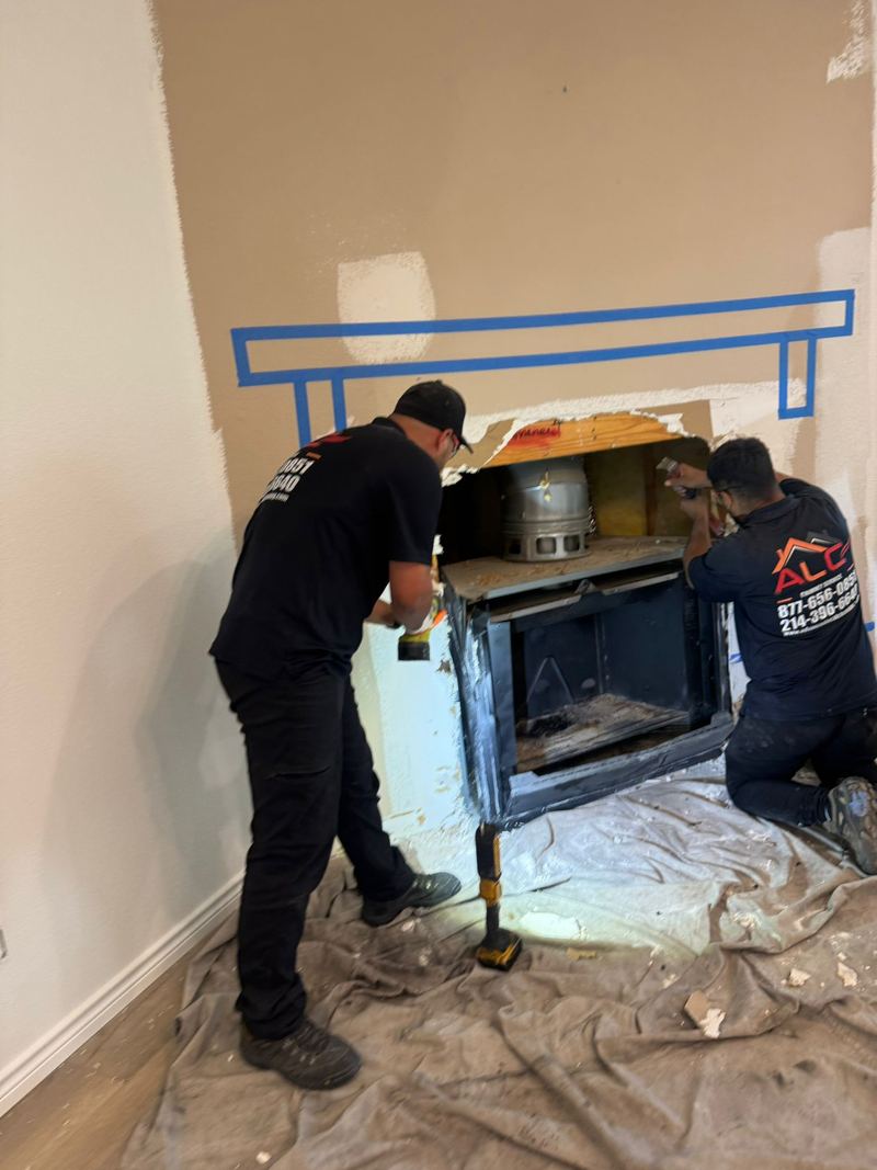 An ALC technician installing a fireplace insert with the floor protected by drop cloths