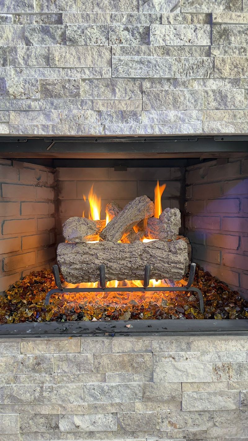 A gas log set burning in a stone surround fireplace after installation
